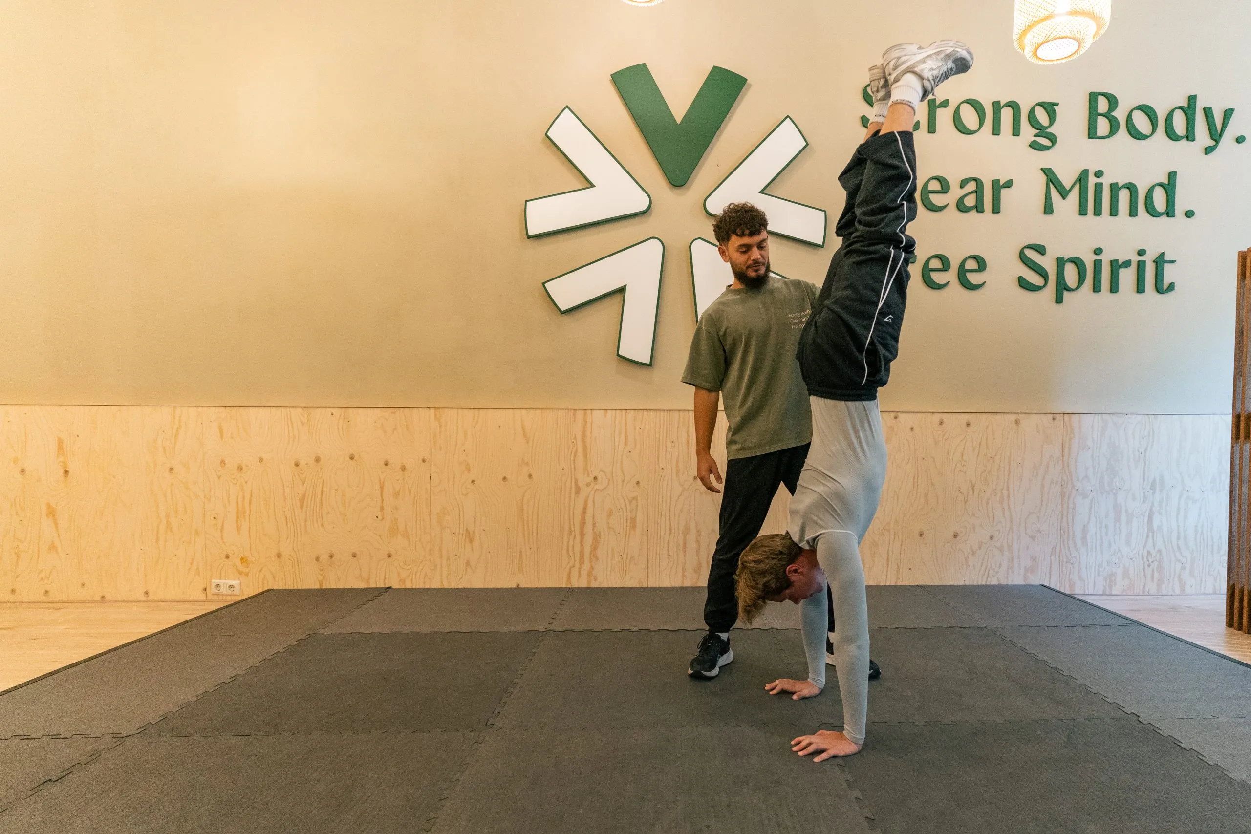 Özgür begeleidt een klant bij een handstand in House of V, Amersfoort