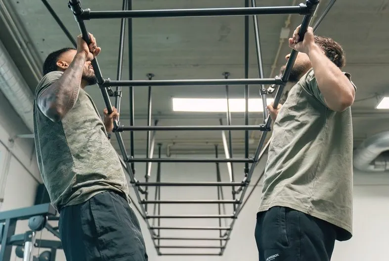 Twee sporters trainen samen aan het pull-uprek tijdens de calisthenics small group in Amersfoort